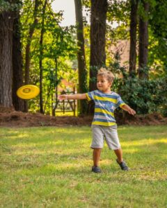 Boy playing outside throwing a yellow frisbee